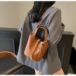 Close-up of brown litchi pattern leather bucket bag with metal lock and crossbody strap