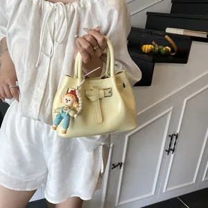 Fashionable cream pleated bucket bag with doll charm shown in a minimalist interior