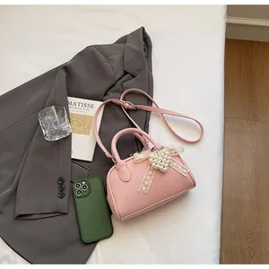 Dettaglio della borsa in pelle rosa con cuore di perle e fiocco in pizzo