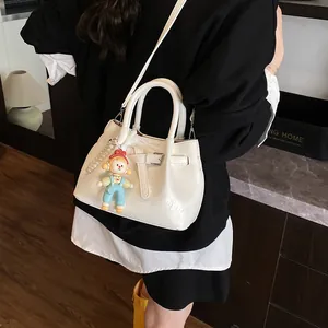 White glossy pleated bucket bag with pearl and cartoon charms shown on a model