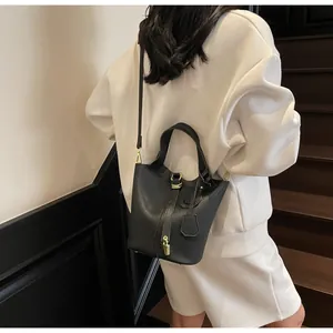 Classic black bucket bag with gold hardware lock and adjustable strap shown on model