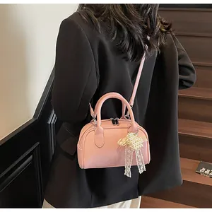 Borsa a tracolla rosa in pelle con ciondolo a perla indossata sopra un blazer nero