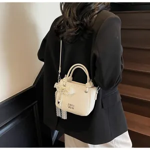Détail du sac seau crème avec cuir grainé et pendentif nœud en dentelle et perles