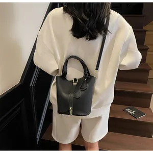 Street style shot of a black lychee pattern leather bucket bag on white outfit back view