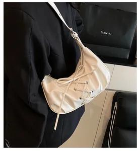 Detailed view of white pleated dumpling bag with cross-straps and bow-knot design