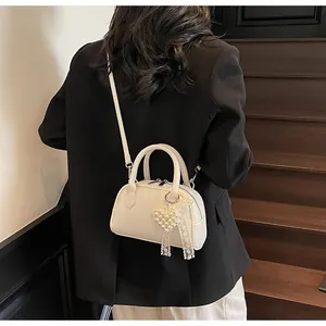Dettaglio di borsa a tracolla bianca con fiocco in pizzo e perle su blazer nero