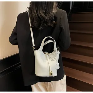 Detail of light grey lychee pattern leather bucket bag with lock and smile charm