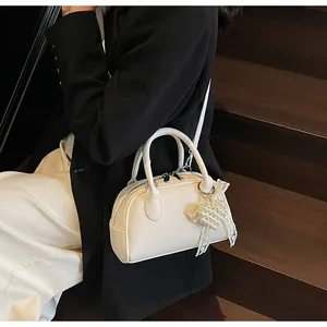 Dettaglio della pelle a grana bianca della borsa Boston con elegante ciondolo di perle