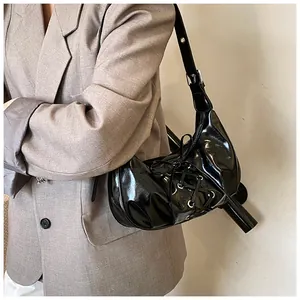Detail shot of black patent leather dumpling bag with decorative lace-up strap details