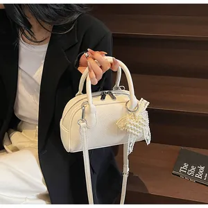 Dettaglio della borsa in pelle bianca con trama litchi, perle e tracolla