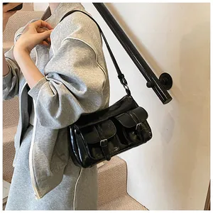 Detail of black glossy faux leather tote bag with silver buckles and flap pockets