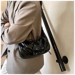Detail of black patent leather hobo bag with stylish lace-up design and glossy finish