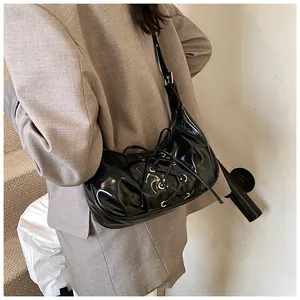 Detail shot of black patent leather bag with silver eyelets and cross lace-up design