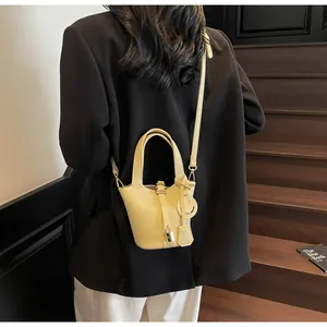 Detail of yellow lychee pattern bucket bag with smiley charm on a black blazer