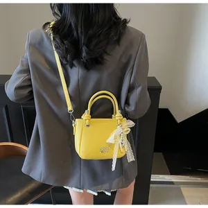 Détail macro du sac seau en cuir jaune avec nœud en dentelle et pendentif perle