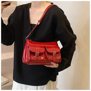Close-up of red patent leather shoulder bag with double buckle pockets and glossy finish