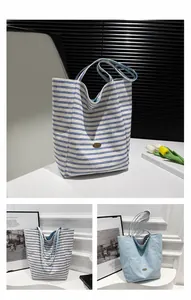 Detalle del bolso tote de lona a rayas azules y blancas con bordado y logo metálico