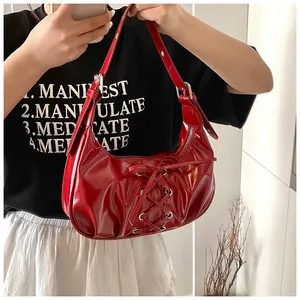 Detail of red glossy patent leather hobo bag with trendy lace-up design and silver buckle
