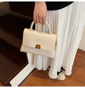 Détail d'un sac à main en cuir grainé crème avec boucle dorée et poignée supérieure