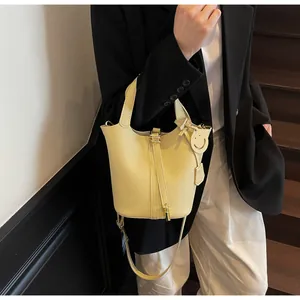 Detail of light yellow bucket bag with pebbled leather texture and metal lock closure