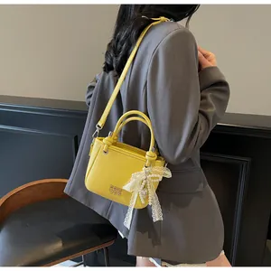 Détail du sac seau en cuir jaune avec nœud en dentelle et pendentif en perles