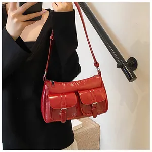 Detail of red patent leather shoulder bag featuring silver buckles and glossy finish