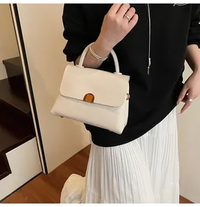 Détail du sac à main blanc en cuir grainé avec fermoir doré et poignée arrondie