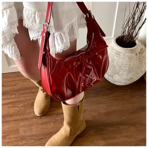 Close-up of a bright red glossy hobo bag with trendy decorative criss-cross lacing detail