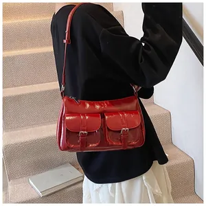 Detail of red patent leather tote bag with double front pockets and pin buckle straps