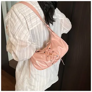 Close-up of pink glossy patent leather shoulder bag with decorative lace-up front detail
