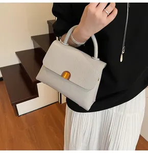 Détail macro d'un sac à main gris clair en cuir avec boucle carrée en métal doré