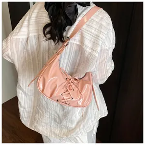 Detail of pink patent leather shoulder bag with lace-up knot and metallic eyelets