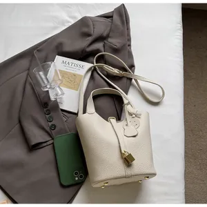 Top view of beige lychee leather bucket bag with gold padlock and detachable shoulder strap