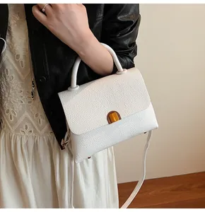 Détail de la sacoche blanche en cuir grainé avec un fermoir métallique doré raffiné