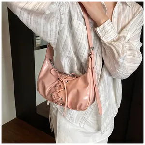 Detail of pink patent leather dumpling bag with tie strap design and silver metal buckle