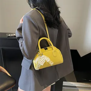 Borsa a tracolla giallo in pelle martellata con ciondolo di perle su modella