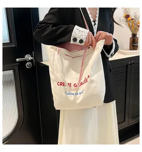 Détail du sac cabas en toile avec lettrage français et anses à rayures sur l'épaule