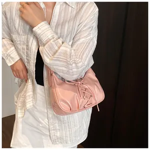 Detailed close-up of pink patent leather shoulder bag with decorative lace-up front detail