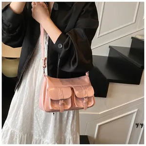 Detail view of pink glossy leather tote with double buckle pockets on a model