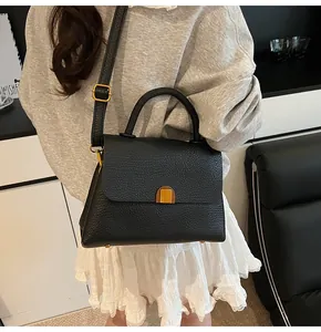 Détail du sac à main en cuir noir grainé avec fermoir doré et bandoulière réglable