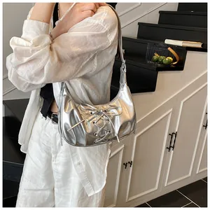 Detailed view of silver metallic crescent bag with trendy lace-up bow and pleated texture