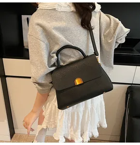 Détail du sac à main en cuir grainé noir avec fermoir doré et pieds de protection