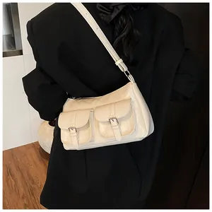 Detail of cream glossy leather tote bag featuring dual flap pockets with silver metal buckles