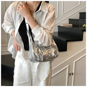 Detail of silver metallic dumpling bag with lace-up straps and liquid gloss finish