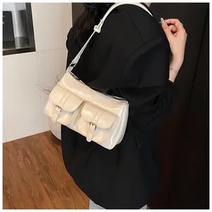 Close-up of cream faux leather shoulder bag with metallic buckle pockets and glossy finish