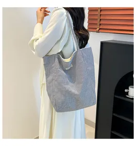 Vue latérale d'un grand sac cabas en toile rayée porté par un mannequin en studio