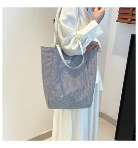 Détail du sac cabas en toile à rayures bleues et blanches montrant la texture et la bandoulière