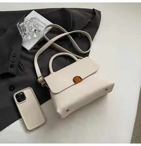 Détail d'un sac à main en cuir grainé blanc avec fermoir doré sur une veste grise