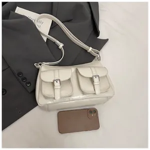 Detail view of cream white PU leather tote with front buckle pockets and metallic hardware