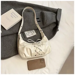 Detail of cream croissant bag featuring lace-up bow knots and premium PU leather texture